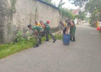 Jelang Nataru, Babinsa Kerja Bakti Bersihkan Sampah Dan Rumput Liar